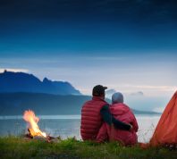 couple sitting by bonfire on camping trip