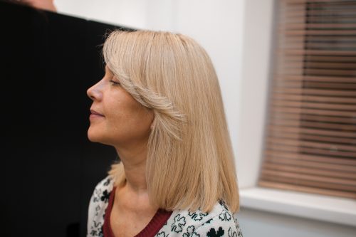 Side profile of a blonde woman with long side-swept bangs