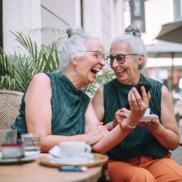 two mature twin women having coffee together outside
