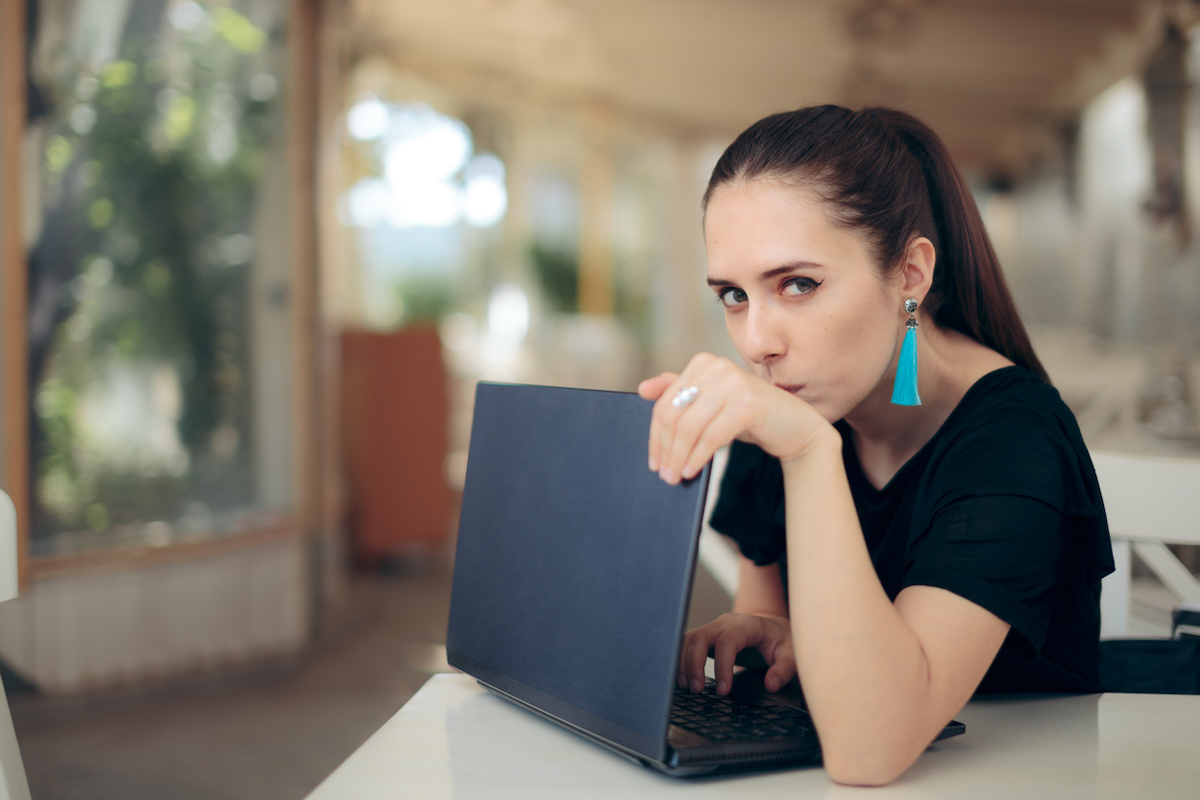 Young woman in a cafe hiding her laptop screen