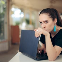 Young woman in a cafe hiding her laptop screen