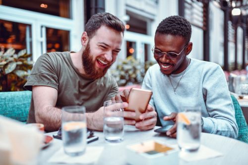 Male Laughing While Browsing Social Media With His Friend