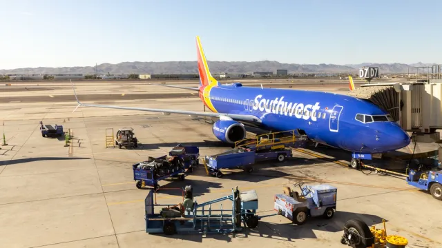 The Phoenix Sky Harbor International Airport runway with a Southwest Airlines plane being loaded at a gate and mountains in the distance.