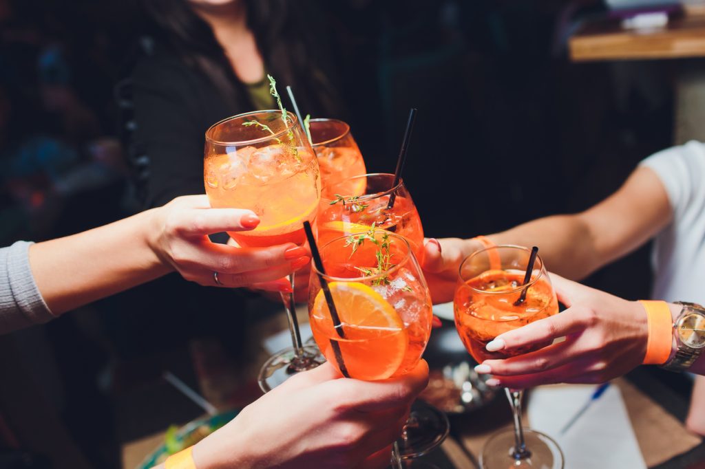 A close up of friends cheersing their spritz cocktails