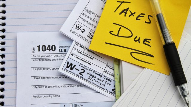A close up of tax forms with a note that says "taxes due" on top