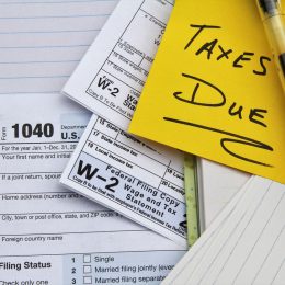 A close up of tax forms with a note that says "taxes due" on top
