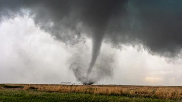 A tornado and dark cloud moving through a field