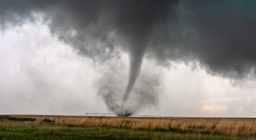 A tornado and dark cloud moving through a field