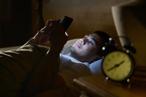 Young man using a smartphone in his bed at night