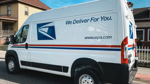 A USPS delivery truck parked on a residential suburban street