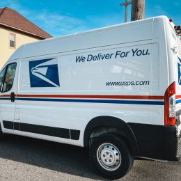 A USPS delivery truck parked on a residential suburban street
