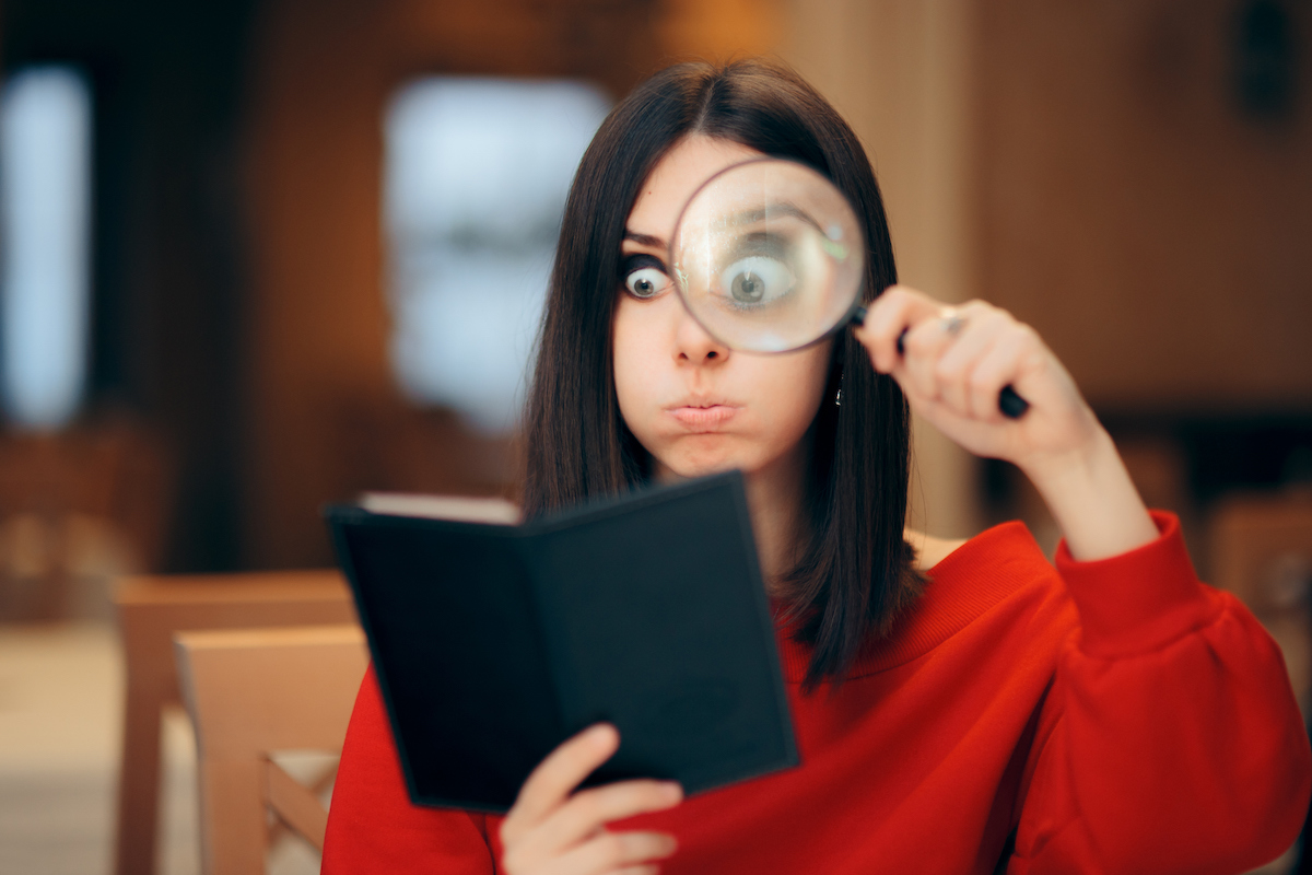 Woman in a red sweater looking at a restaurant bill with a magnifying glass