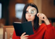 Woman in a red sweater looking at a restaurant bill with a magnifying glass
