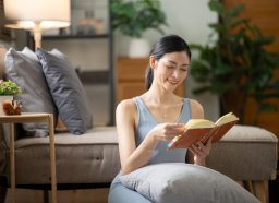 Young woman sitting on the floor reading a book in her reading nook