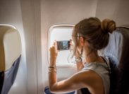 Young woman photographing view from the aircraft window during the flight in the airplane