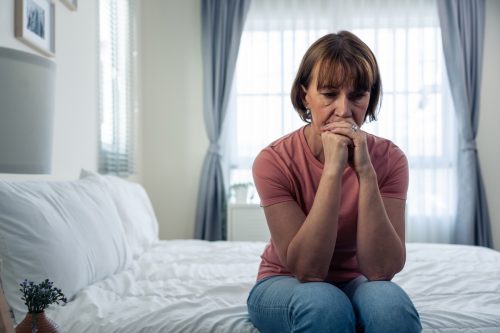 mature woman frustrating while sit alone on bed in bedroom. Attractive old female upset depressed feel infuriating, sad and upset with life problem in house. Health care Medical Concept.