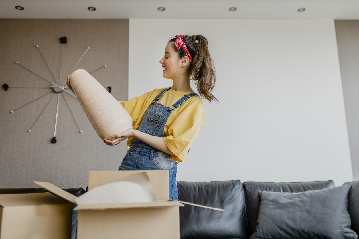 A woman looking at a vase that just arrived in a shipping box