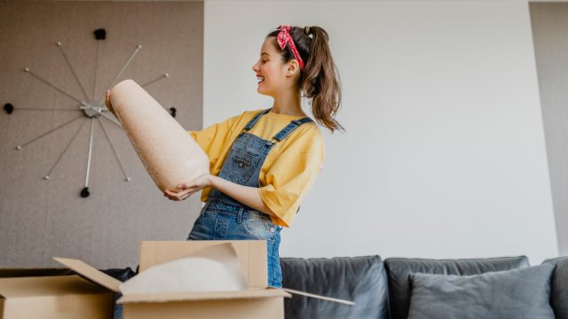 A woman looking at a vase that just arrived in a shipping box