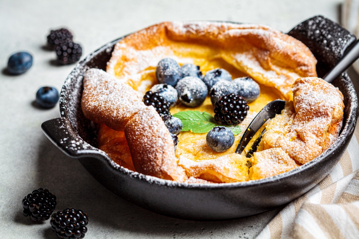 Dutch baby pancake with berries and icing sugar in a pan