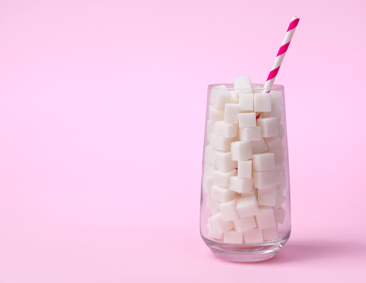 Glass full of sugar cubes on a pink background