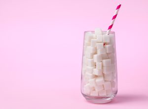 Glass full of sugar cubes on a pink background