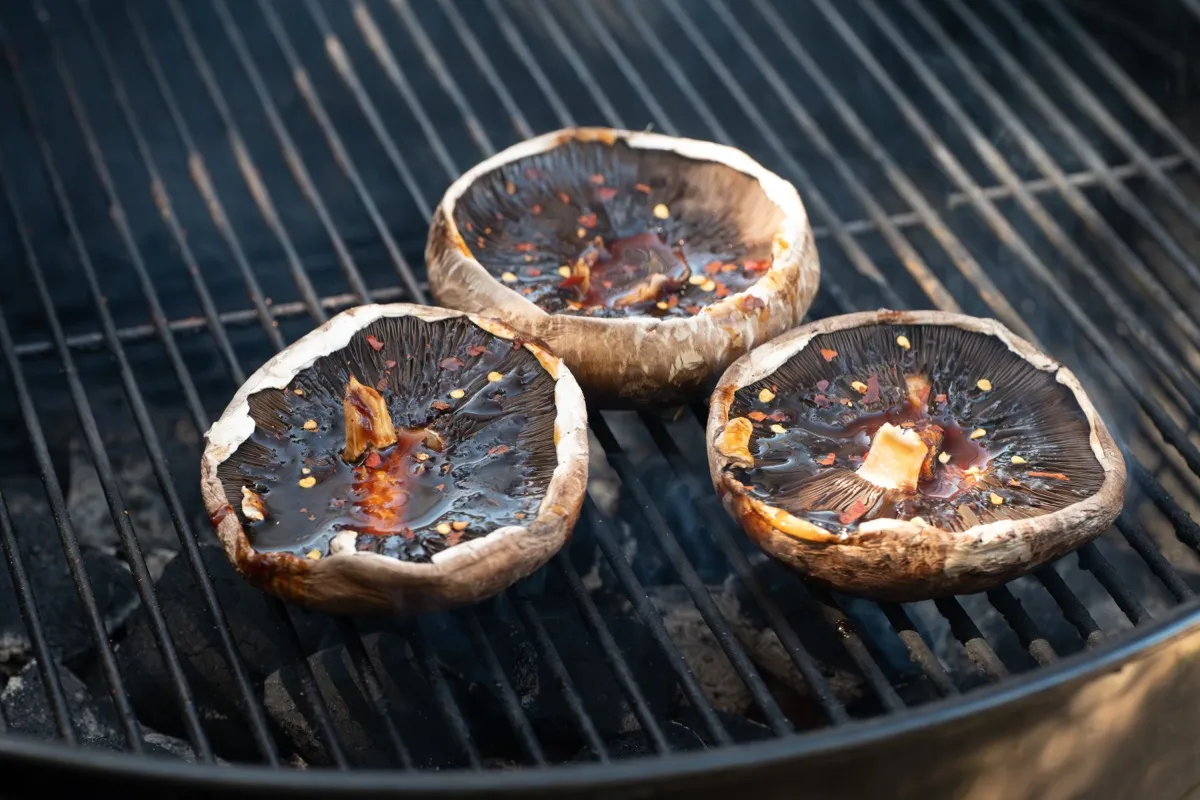 Grilling portobello mushroom caps on a grill outside