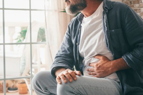 Man suffering with severe stomach pain sitting at home