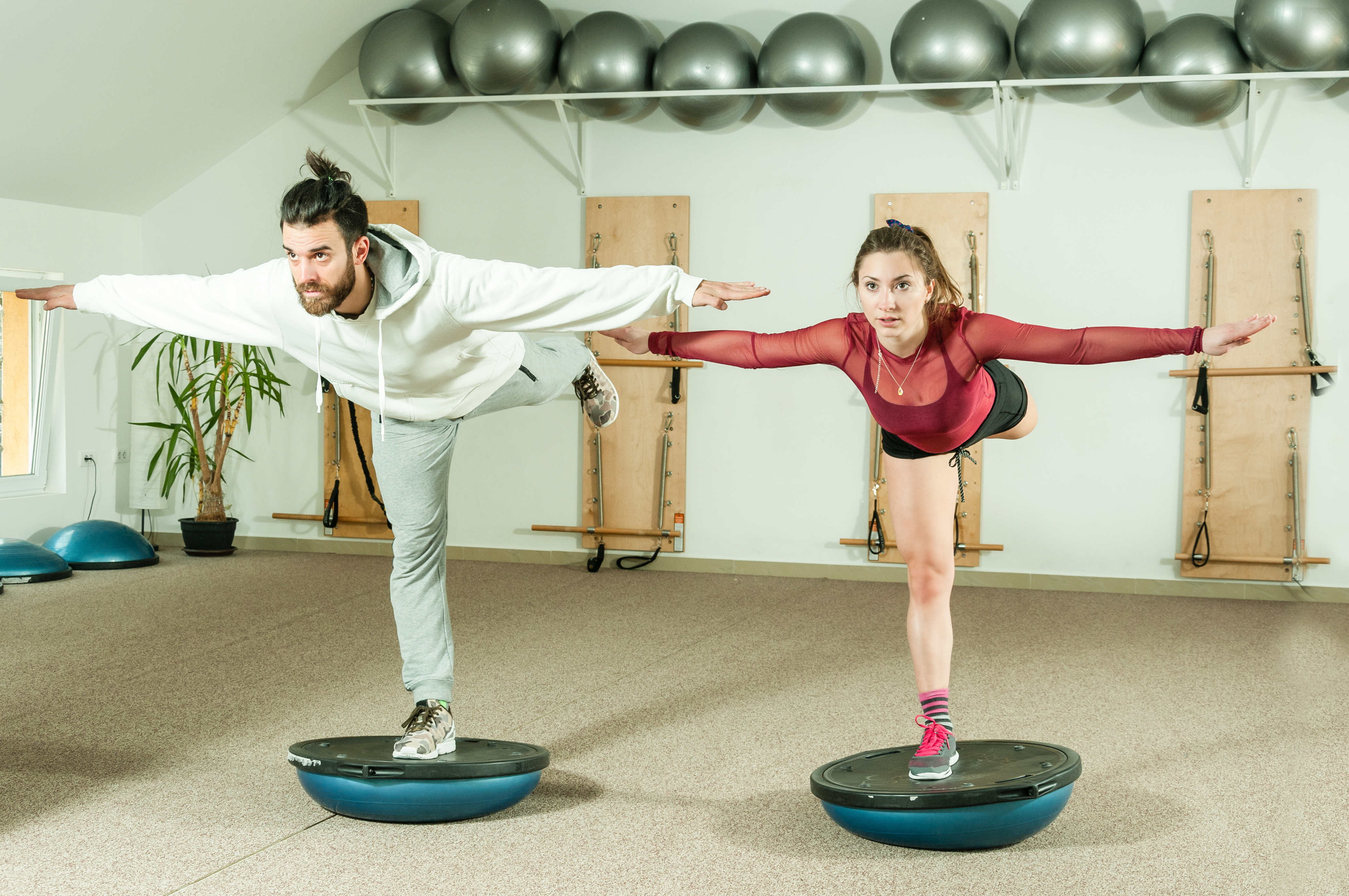 Young couple doing balance exercise on half ball