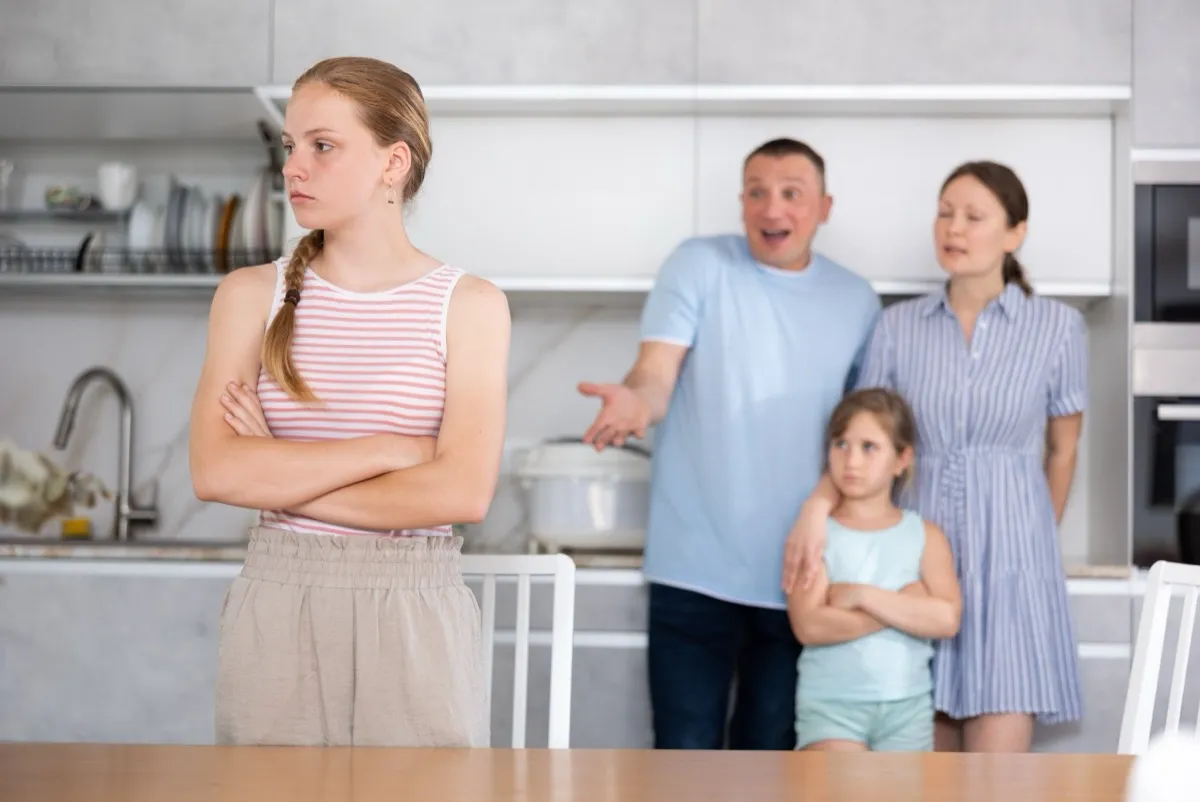 Parents scolding teenager daughter in home kitchen
