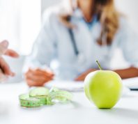 closeup blurred image of weight-loss doctor talking to a patient with an apple on the table