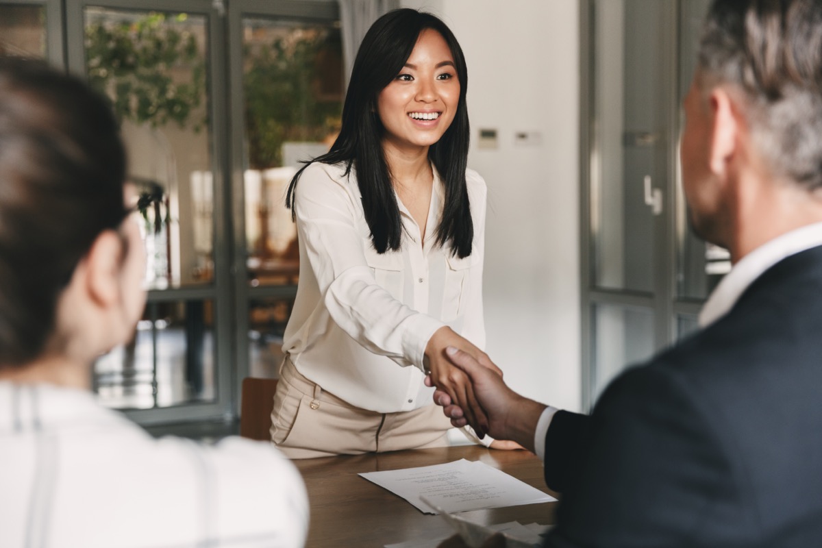 Woman smiling and shaking hands at job interview