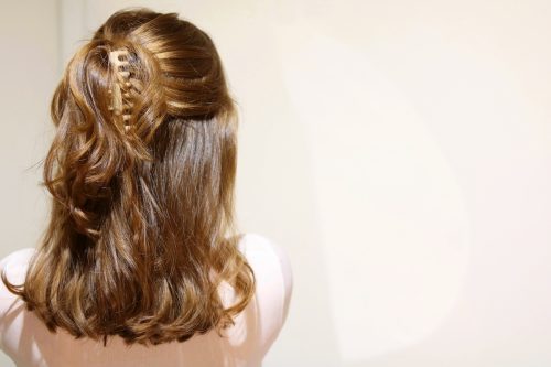Rear view of woman with brown hair pulled half-up in beige claw clip. 