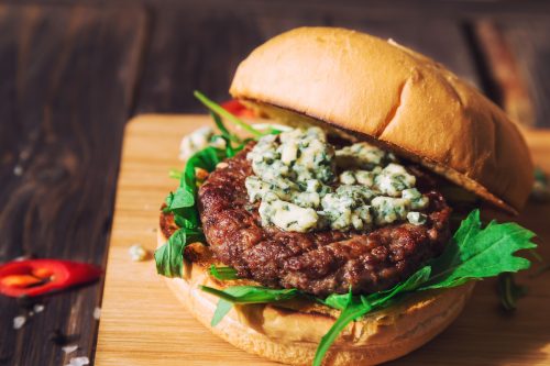 burger with blue cheese and arugula on rustic wooden background