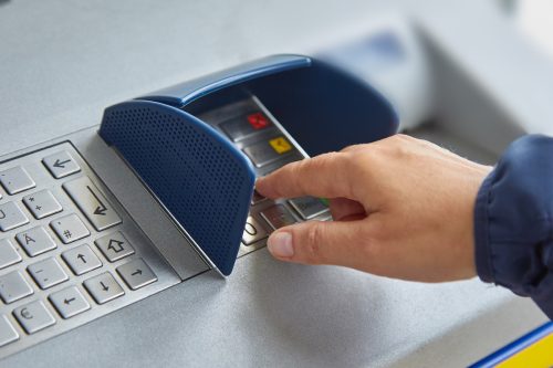 A female hand dials a personal code on the ATM keyboard. The concept of safe use of bank cards, deductible funds, the wholesale of services and goods, receiving cash.
