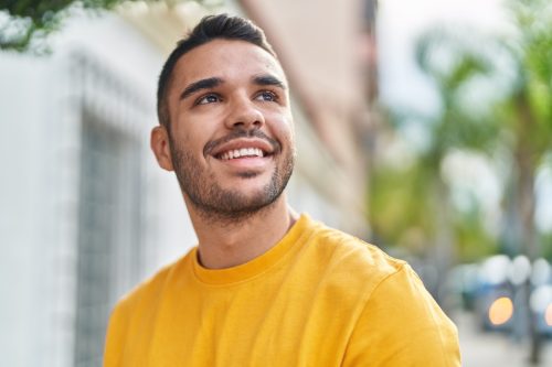 Young man smiling confident looking to the sky at street