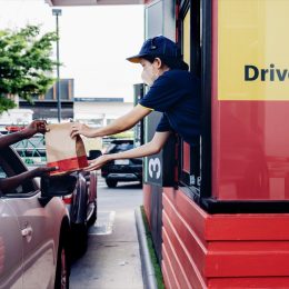Hand Man in car receiving coffee in drive thru fast food restaurant. Staff serving takeaway order for driver in delivery window. Drive through and takeaway for buy fast food for protect covid19.