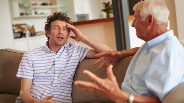 Father and son sitting on the couch having a disagreement