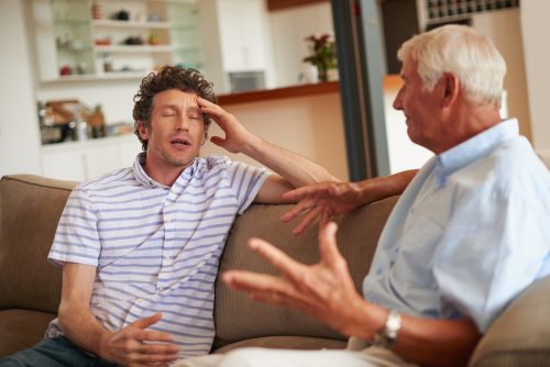 Father and son sitting on the couch having a disagreement