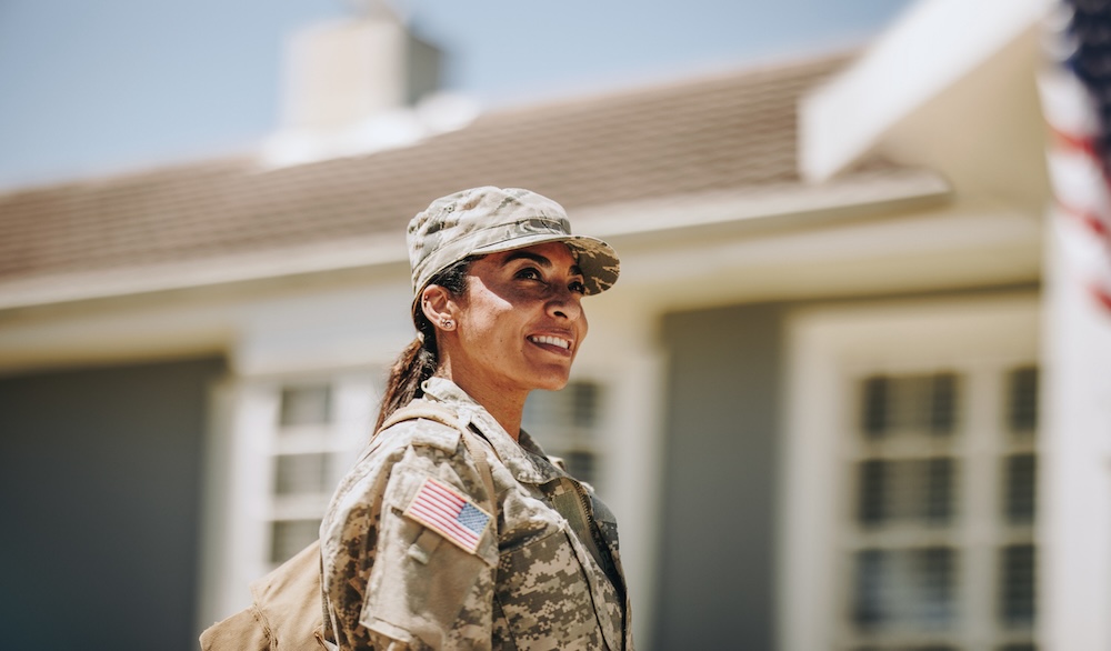A female soldier standing in front of a house