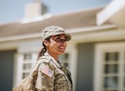 A female soldier standing in front of a house