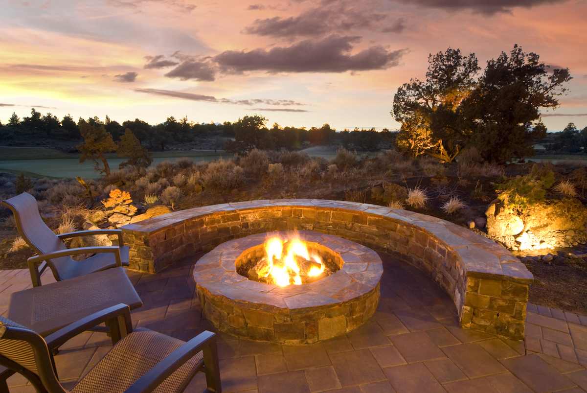 stone fire pit with outdoor chairs, enjoying the sunset and landscape.