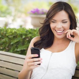 woman smiling while reading good afternoon greetings from her phone