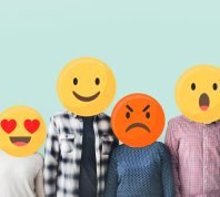People standing in a row with their faces covered by emojis