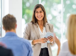 smiling woman speaking in front of peers