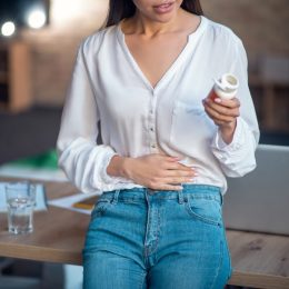 Feeling pain. Pleasant young woman putting hand on her stomach while feeling pain in it