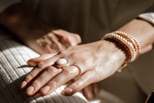 Close up picture of womans hand with gold jewelry.