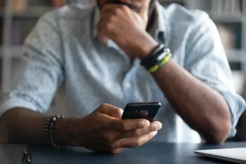 man holding his phone thinking about sending text