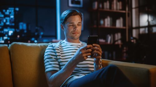 man texting on phone late at night while sitting on couch