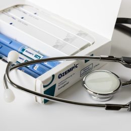 box of ozempic injectable pens alongside a stethoscope on a white background