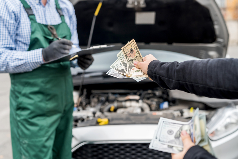 A close up of a person handing a mechanic money to fix their car